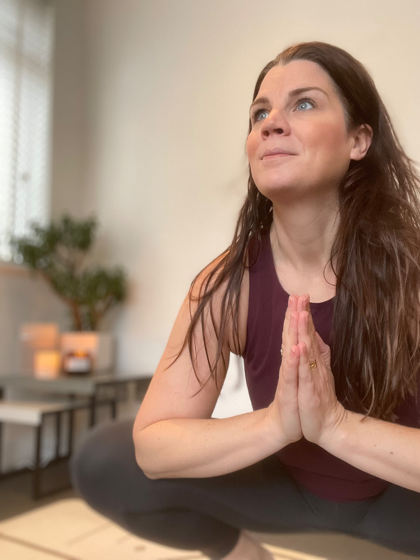 Liz, yoga teacher and creator of Sequence/OS, seated with hands at heart centre